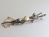 a close up of a brooch with pearls and leaves