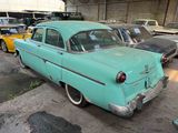 many old cars parked in a garage with other cars