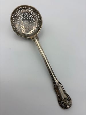 an antique silver spoon with a handle on a white surface