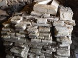 a pile of bricks sitting on the ground next to a stone wall