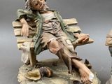 two figurines of a man sitting on a bench