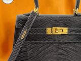 an image of a black handbag with a gold handle