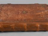 an old book with a leather cover sitting on top of a table