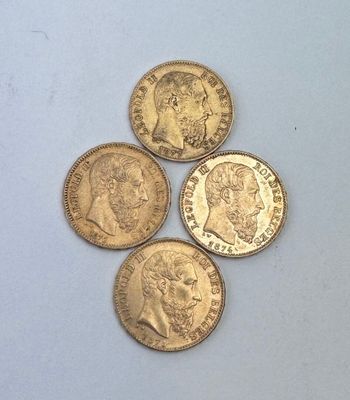 quatre types différents de pièces d'or reposant sur une surface blanche