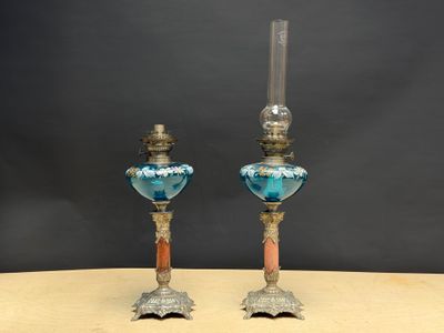 une paire de bougeoirs en verre bleu posés sur une table en bois, sur fond noir