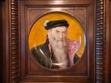 painting of a bearded man in a wooden frame with a yellow background