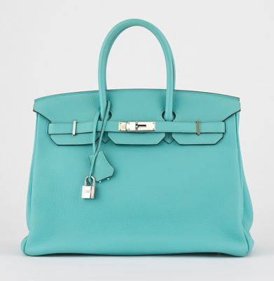 un sac à main en cuir bleu muni d'un cadenas sur la poignée