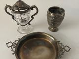 un plateau en argent sur lequel sont posés une tasse et un vase en argent, sur une table blanche