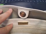 a hand that is holding a purse in front of a laptop