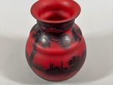 a red vase with black designs on it on a white surface
