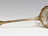 cuillère plaquée argent avec un manche en forme de coquillage sur un fond blanc