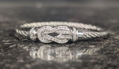 une bague en argent ornée d'un nœud, posée sur une table