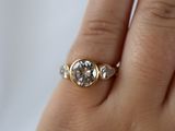 a woman ' s hand holding a ring with a diamond on it