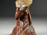 a close up of a statue of a person sitting on a rock