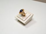 an image of a gold ring with a blue stone in it