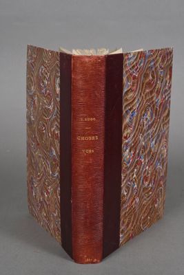 an old book with a red cover sitting on top of a table