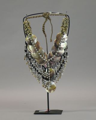 necklace made of shells and pearls on a stand on a gray background