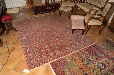 des tapis et des fauteuils dans un salon où se trouve un téléviseur posé sur un meuble TV