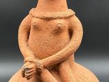 une image représentant une figurine en argile représentant une femme assise sur un rocher