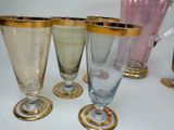 five glasses and a pitcher sitting on a table