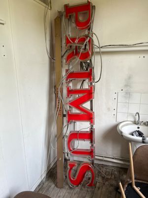 une grande enseigne rouge portant l'inscription « Brims » fixée sur le côté d'un mur