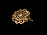 a close up of a gold flower broochle on a black surface