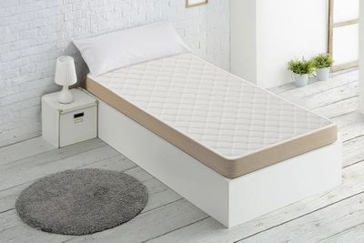 a bed with a mattress and a rug on the floor