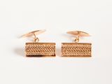 a pair of gold cufflinks on a white background