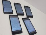 four cell phones are lined up on a white table