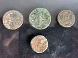 four ancient roman coins sitting on a black surface next to each other