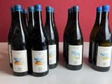 six bouteilles de vin sont posées sur une table devant un mur rouge