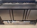 trois réfrigérateurs en acier inoxydable posés sur un plan de travail dans une cuisine