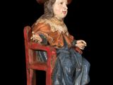 wooden statue of a boy sitting on a bench with a hat on