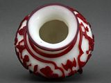 a red and white vase sitting on a gray surface