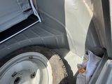 un camion blanc dont la porte est ouverte et qui transporte un pneu à l'arrière