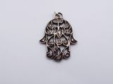 a silver hamsa pendant with an intricate design on a white background