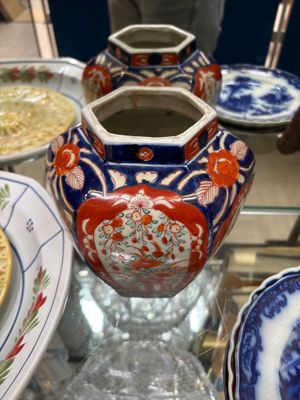 de nombreuses assiettes et vases posés sur une table en verre, avec un homme en arrière-plan