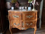 a wooden dresser with a marble top and a candle on it