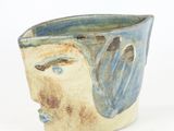 a close up of a vase with a face on it