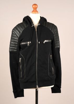 La veste est noire et comporte des fermetures éclair sur les manches.