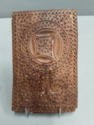 plaque en bois sculptée surmontée d'un vase, posée sur un fond blanc