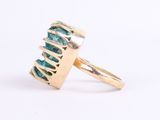 a close up of a gold ring with a green stone in it