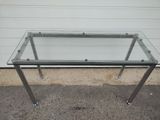 a glass table with metal legs and a glass top
