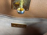 the inside of a brown purse with a gold metal handle