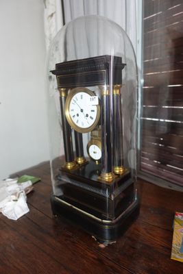 une horloge posée sur une table, protégée par une vitre