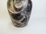 un vase noir et blanc posé sur une surface blanche