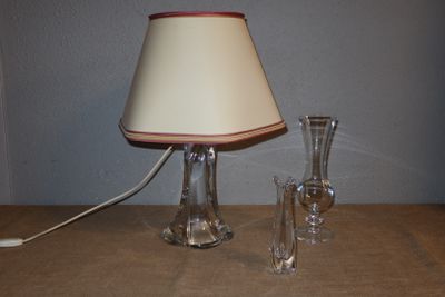 une lampe posée sur une table à côté d'un vase en verre