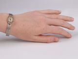 wrist of a woman with a watch on it ' s wrist on a white surface