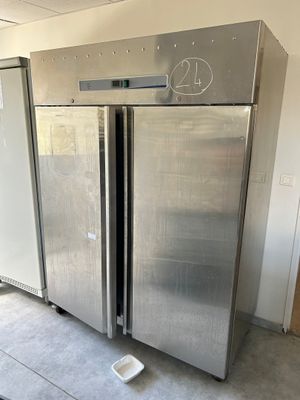 two stainless steel refrigerators in a room with concrete flooring
