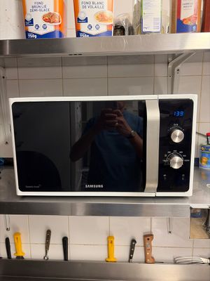 a man taking a picture of himself in the mirror of a microwave